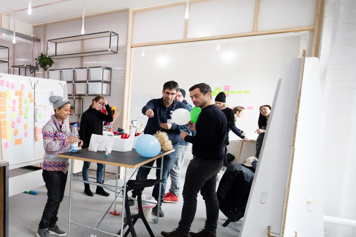 Teilnehmende arbeiten in Kleingruppen an Stehtischen und Whiteboards im White Space von Dark Horse
