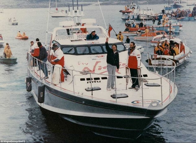 Richard Branson winkt an Bord seines Rekord-Schnellboots Virgin Atlantic Challenger, umringt von einer Flotte begleitender Boote im Hafen