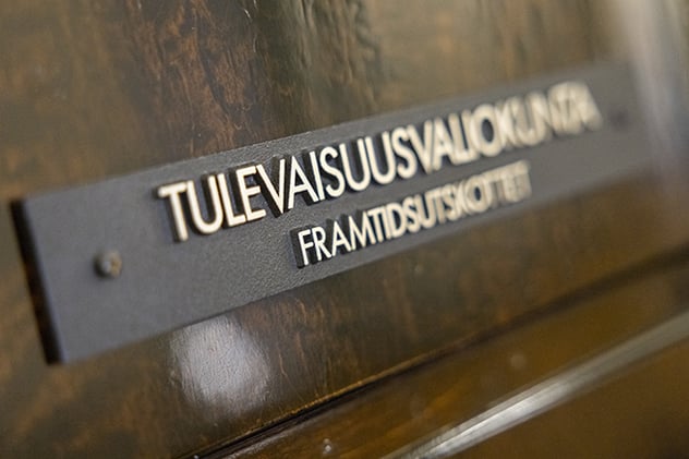 Messingschild an einer dunklen Holztür im finnischen Parlament mit der Aufschrift Tulevaisuusvaliokunta / Framtidsutskottet – dem Zukunftsausschuss
